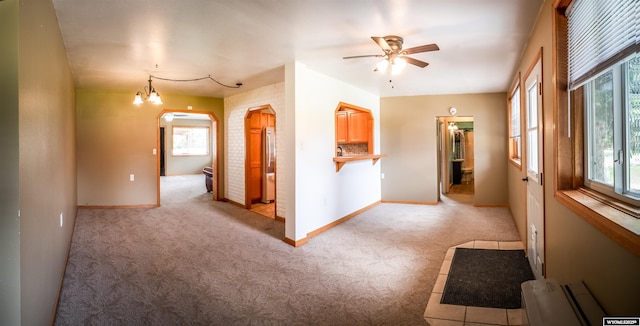 hall with arched walkways, light colored carpet, and baseboards