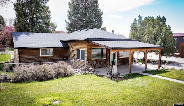 view of front of house featuring a patio area, a shingled roof, fence, and a front yard