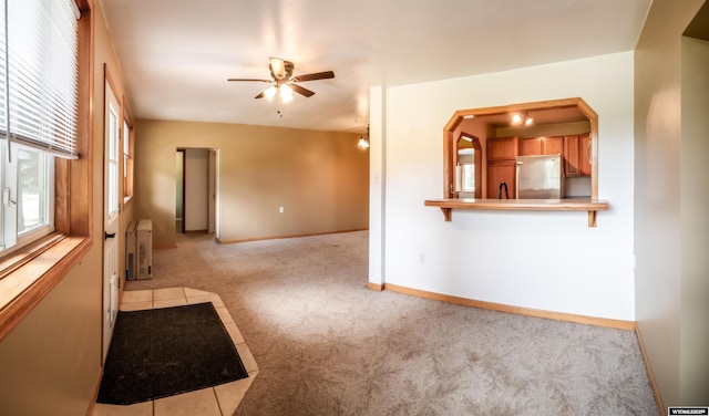 carpeted empty room with ceiling fan and baseboards