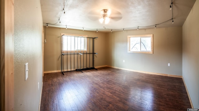 unfurnished room featuring rail lighting, a ceiling fan, and dark wood-style flooring