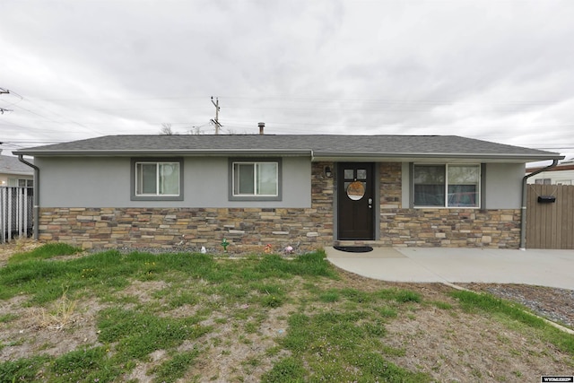 view of front of property with fence, a shingled roof, stucco siding, and stone siding
