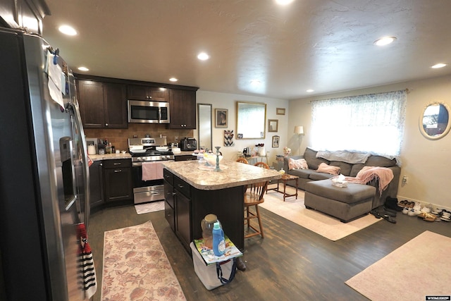 kitchen with a breakfast bar, open floor plan, light countertops, a center island, and appliances with stainless steel finishes