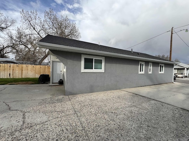 822 W St, Rock Springs, WY 82901 - view of property exterior with stucco siding, fence, a patio, and a shingled roof