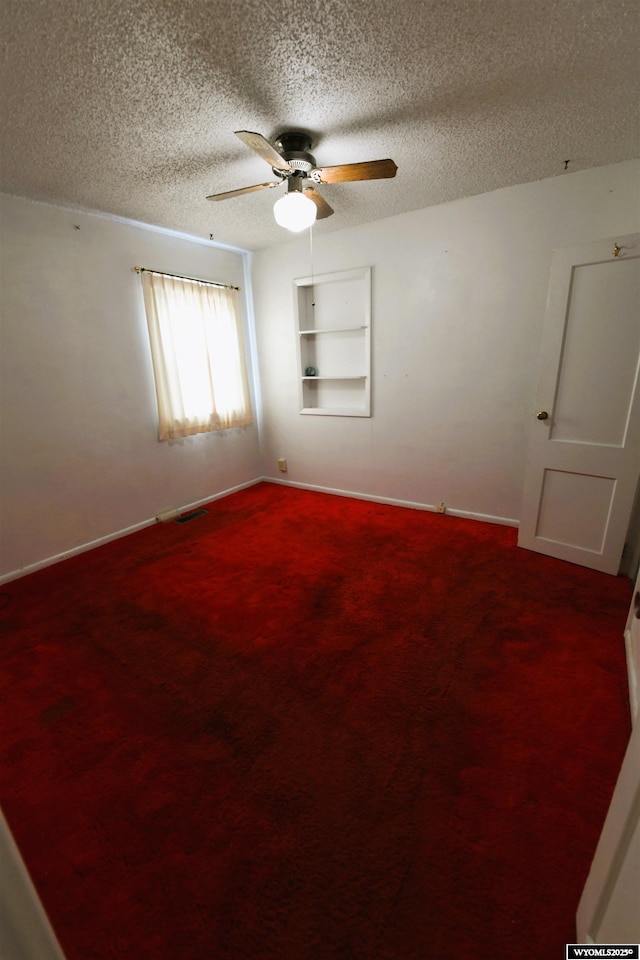 unfurnished room featuring a ceiling fan, carpet, a textured ceiling, baseboards, and visible vents