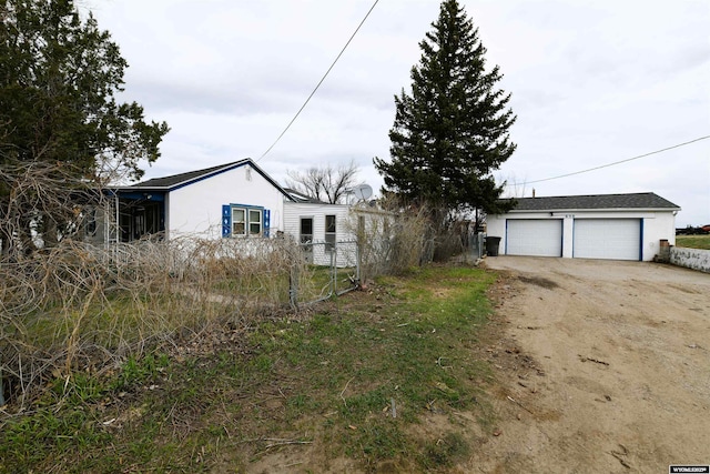 view of front facade with an outbuilding, stucco siding, a garage, and fence