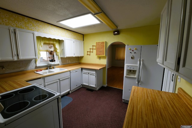 kitchen featuring white appliances, wooden counters, dark colored carpet, a sink, and arched walkways