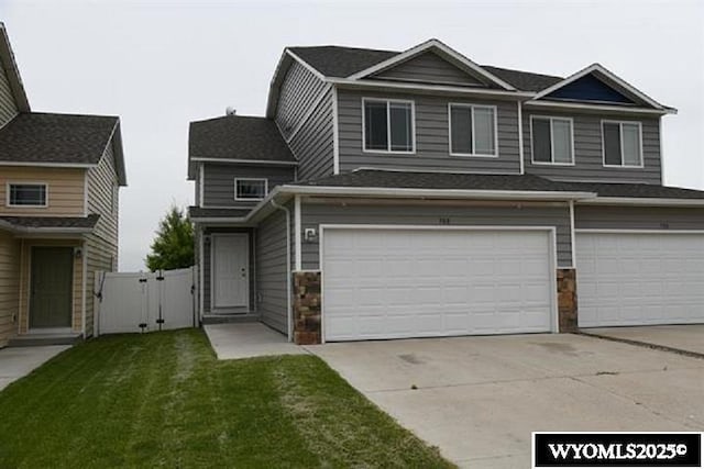 70B 27th St, Wheatland, WY 82201 - view of front of property with an attached garage, stone siding, a gate, concrete driveway, and a front yard