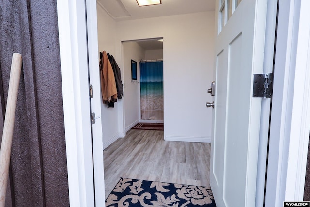 hall with baseboards and light wood-style floors