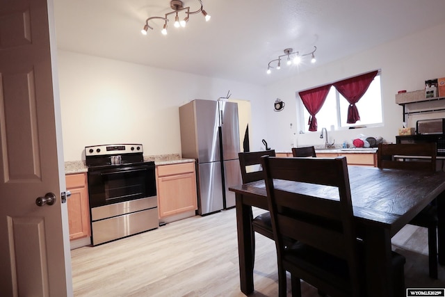 kitchen with a notable chandelier, light brown cabinets, light stone countertops, light wood finished floors, and appliances with stainless steel finishes