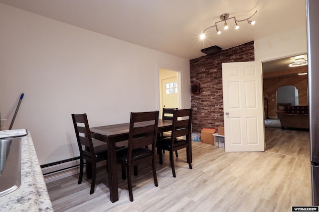 dining space with a baseboard radiator and light wood-style flooring