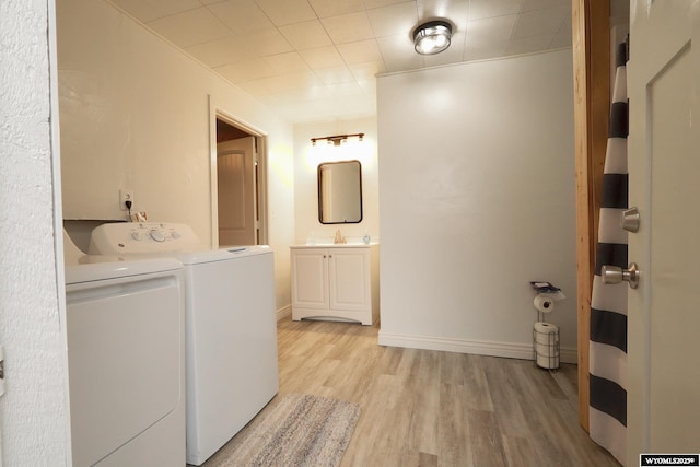 laundry room with washer and dryer, light wood-style flooring, a sink, laundry area, and baseboards