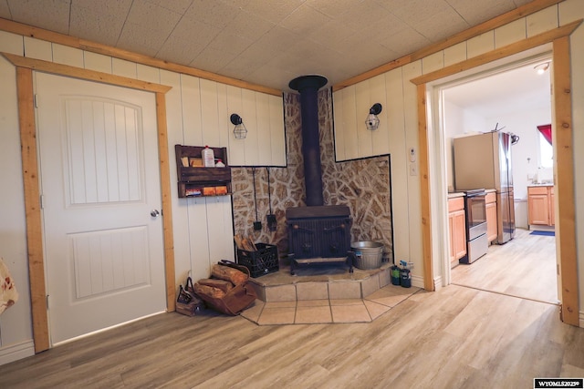 living room featuring a wood stove, wood walls, and light wood finished floors