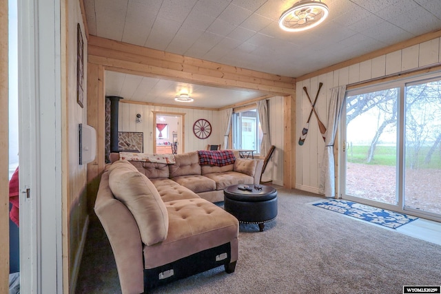 living room with a wood stove, wood walls, and carpet