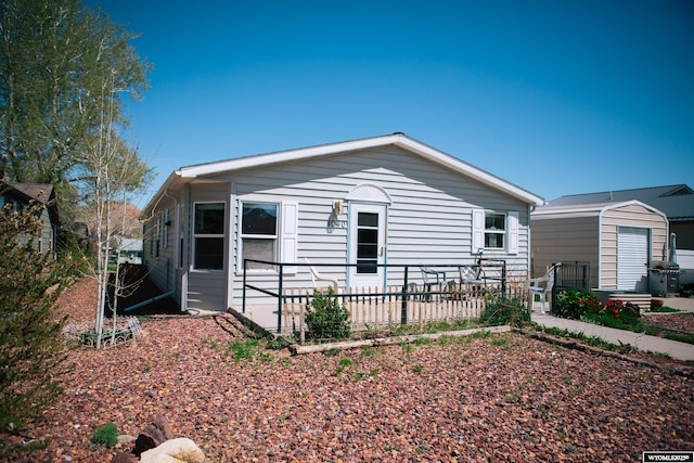 view of front of house featuring fence, a patio area, and an outbuilding