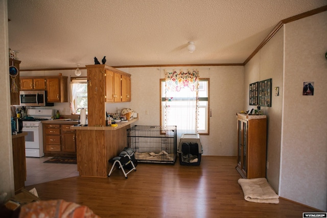 kitchen featuring stainless steel microwave, crown molding, gas range gas stove, and wood finished floors