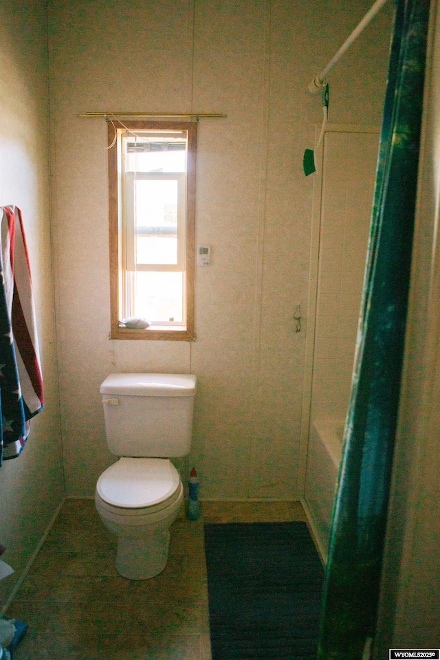 bathroom featuring toilet and shower / bath combination with curtain