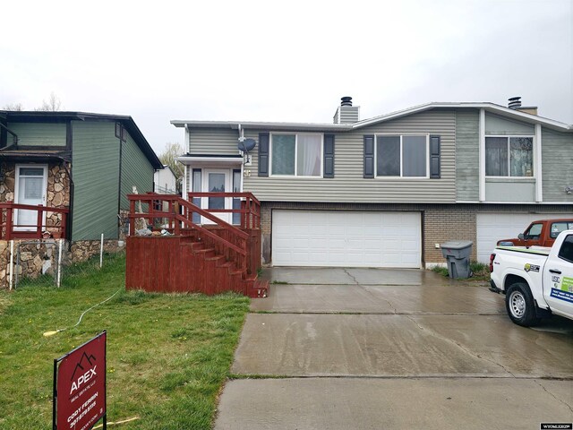 117 Sandstone Dr, Evanston, WY 82930 - split level home featuring a chimney, driveway, brick siding, a garage, and a front lawn