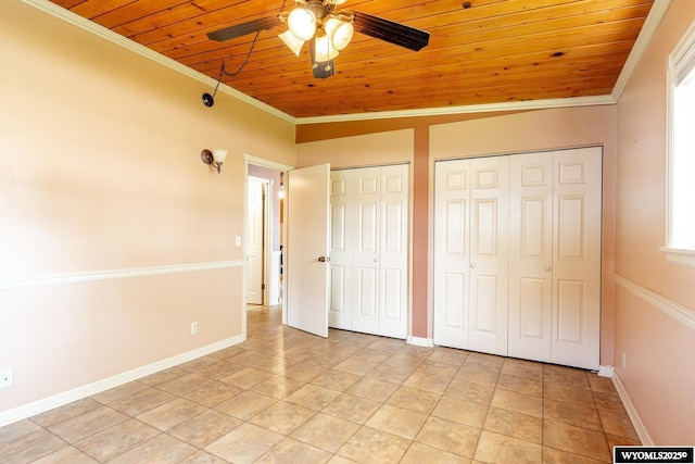 unfurnished bedroom featuring crown molding, wood ceiling, baseboards, and multiple closets
