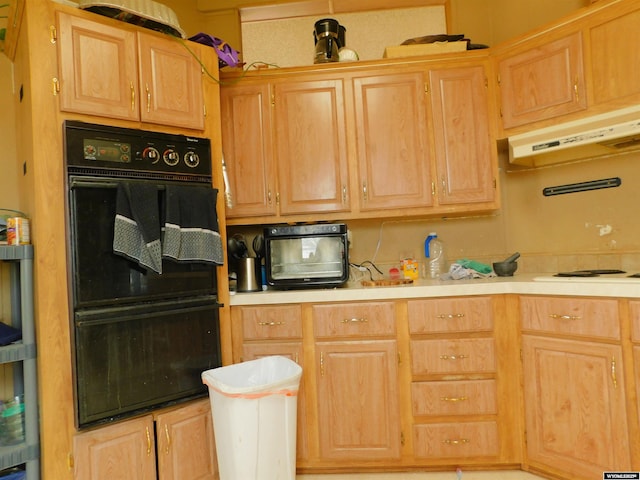 479 Hoskins Ln, Rock Springs, WY 82901 - kitchen with white electric stovetop, under cabinet range hood, light countertops, dobule oven black, and light brown cabinets