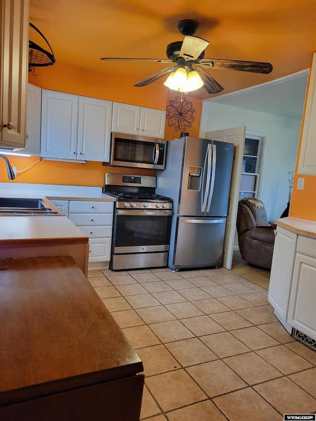 1001 Country Club Rd, Casper, WY 82609 - kitchen with appliances with stainless steel finishes, a ceiling fan, a sink, light tile patterned floors, and white cabinetry