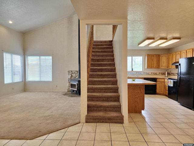kitchen with light colored carpet, light countertops, black appliances, and light tile patterned floors