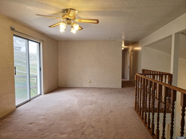 carpeted empty room with ceiling fan and a textured ceiling