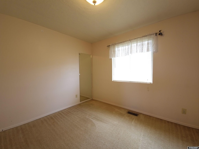 empty room with baseboards, visible vents, and carpet