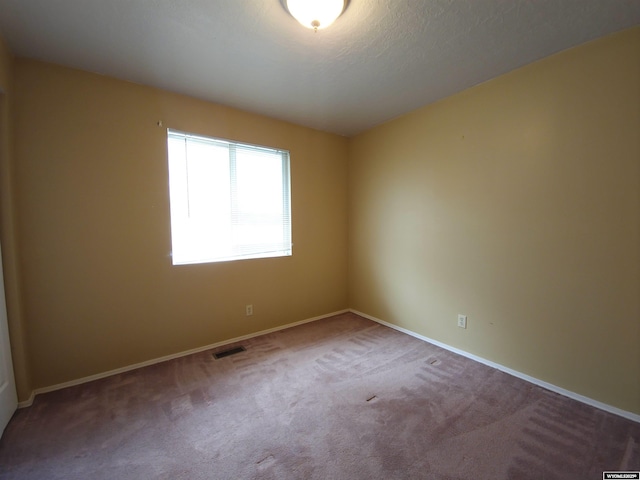 carpeted spare room with visible vents and baseboards