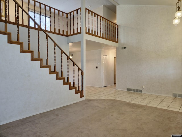 stairs with a towering ceiling, carpet flooring, visible vents, and tile patterned floors