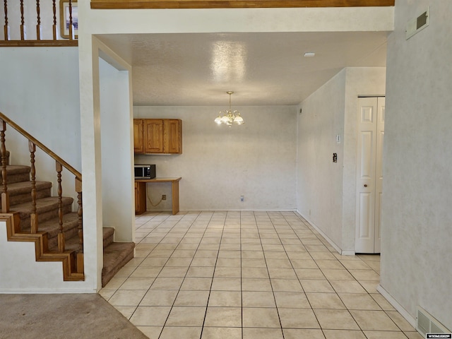interior space featuring light tile patterned flooring, a chandelier, visible vents, and stairway