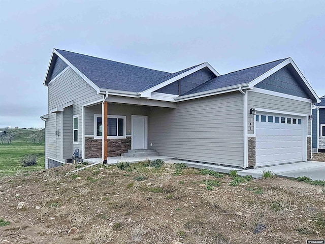 craftsman-style house featuring stone siding, an attached garage, and concrete driveway