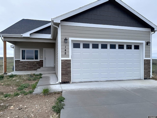 148 White Tail Ct, Buffalo, WY 82834 - view of front of home featuring stone siding, driveway, and a garage