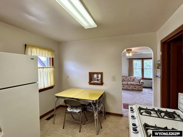 kitchen featuring freestanding refrigerator, baseboards, light tile patterned floors, and gas range oven