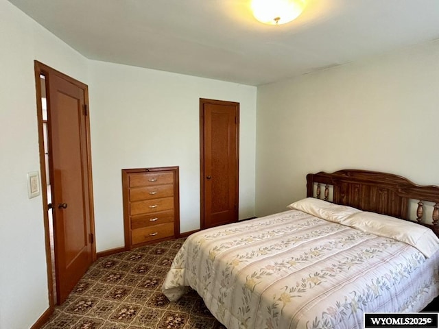 bedroom with dark colored carpet, a closet, and baseboards