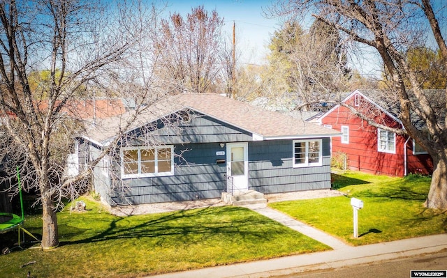 view of front facade featuring a shingled roof, a front yard, and entry steps