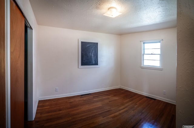 unfurnished bedroom with dark wood finished floors, baseboards, a closet, and a textured ceiling