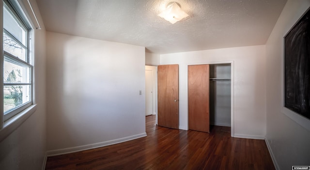 unfurnished bedroom featuring dark wood-type flooring, baseboards, a closet, and a textured ceiling