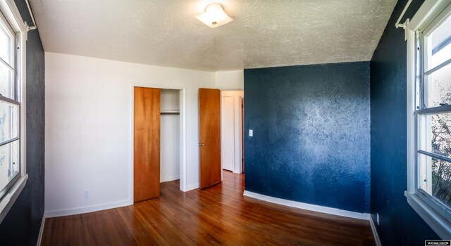 unfurnished bedroom with wood finished floors and baseboards