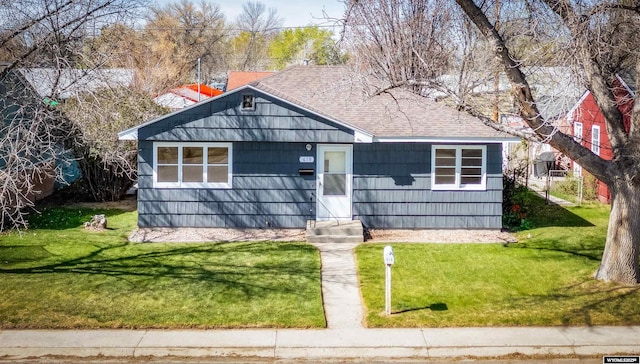 bungalow-style home with entry steps, a shingled roof, and a front yard