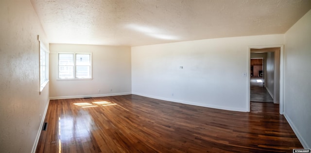 unfurnished room featuring a textured ceiling, dark wood-type flooring, and baseboards