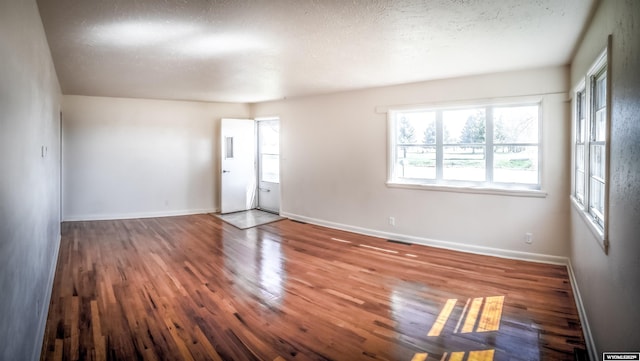unfurnished room featuring wood finished floors, baseboards, and a textured ceiling