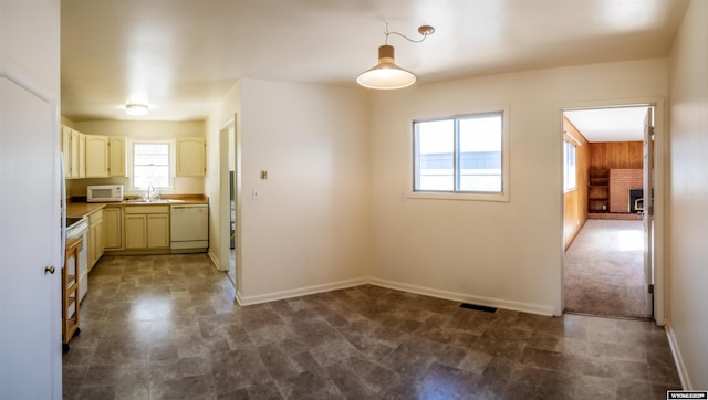 kitchen with white appliances, a sink, baseboards, and pendant lighting