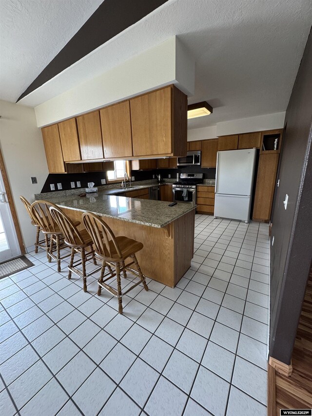 191 Lester Dr, Rock Springs, WY 82901 - kitchen with stainless steel appliances, a peninsula, a textured ceiling, a sink, and light tile patterned flooring