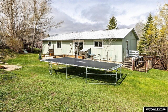 147 Apache Dr, Evanston, WY 82930 - rear view of house featuring a trampoline, a lawn, and metal roof