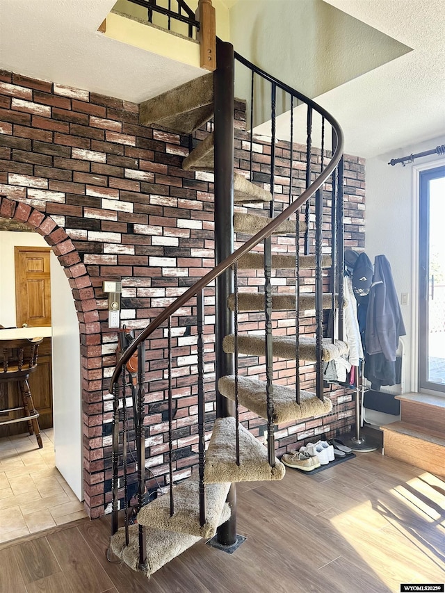 stairway featuring wood finished floors, arched walkways, and a textured ceiling