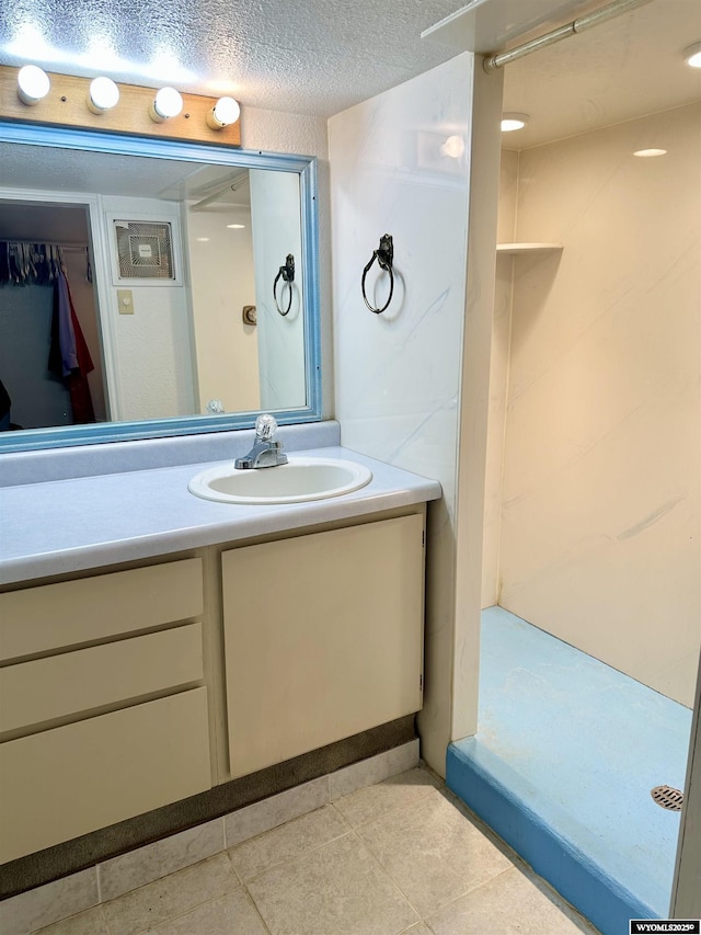 bathroom with vanity, a shower, tile patterned flooring, and a textured ceiling