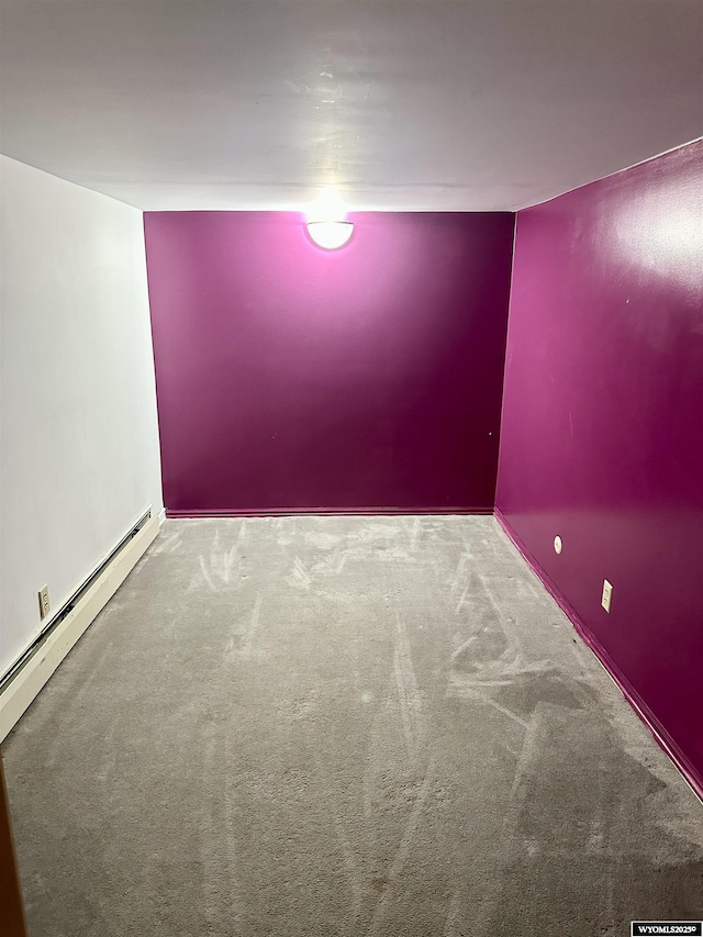 spare room with carpet flooring and a baseboard heating unit