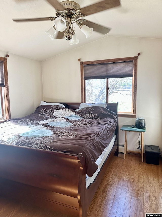 bedroom with lofted ceiling, wood finished floors, ceiling fan, and baseboard heating