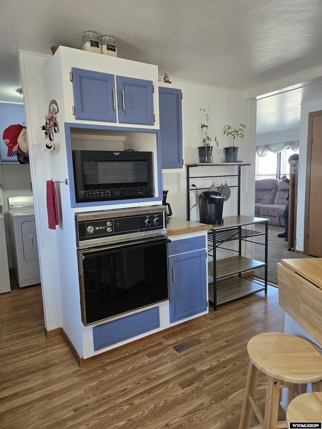 716 E 3rd St, Marbleton, WY 83113 - kitchen with black appliances, washer / clothes dryer, blue cabinets, dark wood-style floors, and light countertops