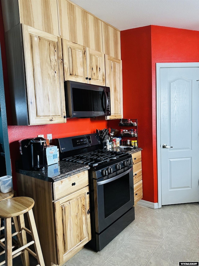 65 Eagle Ln, Lyman, WY 82937 - kitchen with stainless steel gas range, dark stone countertops, and light brown cabinetry